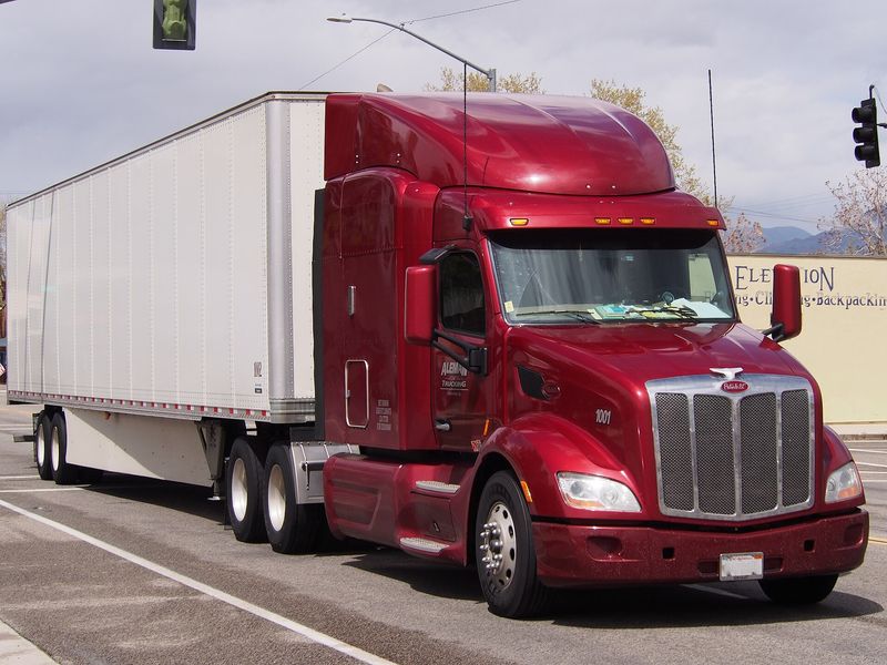 Red Peterbilt 579 pulling a white dry-van trailer