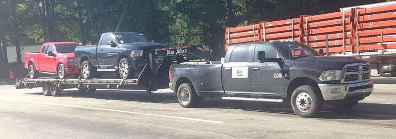 Black 2014-2016 Ram 3500 Cummins crew cab dually towing a car-hauler trailer
